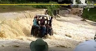 Trabalhadores rurais de Chã Grande se arriscam atravessando trecho de estrada banhado por barragem que transbordou com as chuvas; problema é recorrente