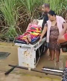 Idosa sendo socorrida em transporte improvisado durante alagamento em Sertãozinho de Baixo, Maraial