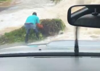 Chã Grande: homem se arrisca ao desobstruir estrada tomada pela força das águas que desaguam da Barragem de Vertentes