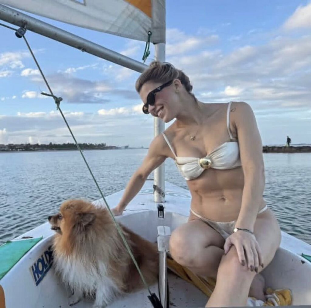 Advogada Maria Eduarda “Duda” Medeiros aparece sorrindo ao lado de seu cão durante passeio de embarcação no mar, antes do naufrágio ocorrido na região de Suape, em Pernambuco.