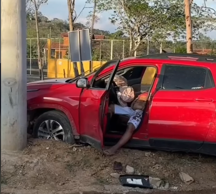 Imagem do veículo conduzido pelo ex-policial militar Jailson Carcará colidido contra um poste na estrada da Serra do Maroto, em Gravatá. O carro apresenta marcas de colisão e o cenário mostra o isolamento da área após a execução com tiros de fuzil.