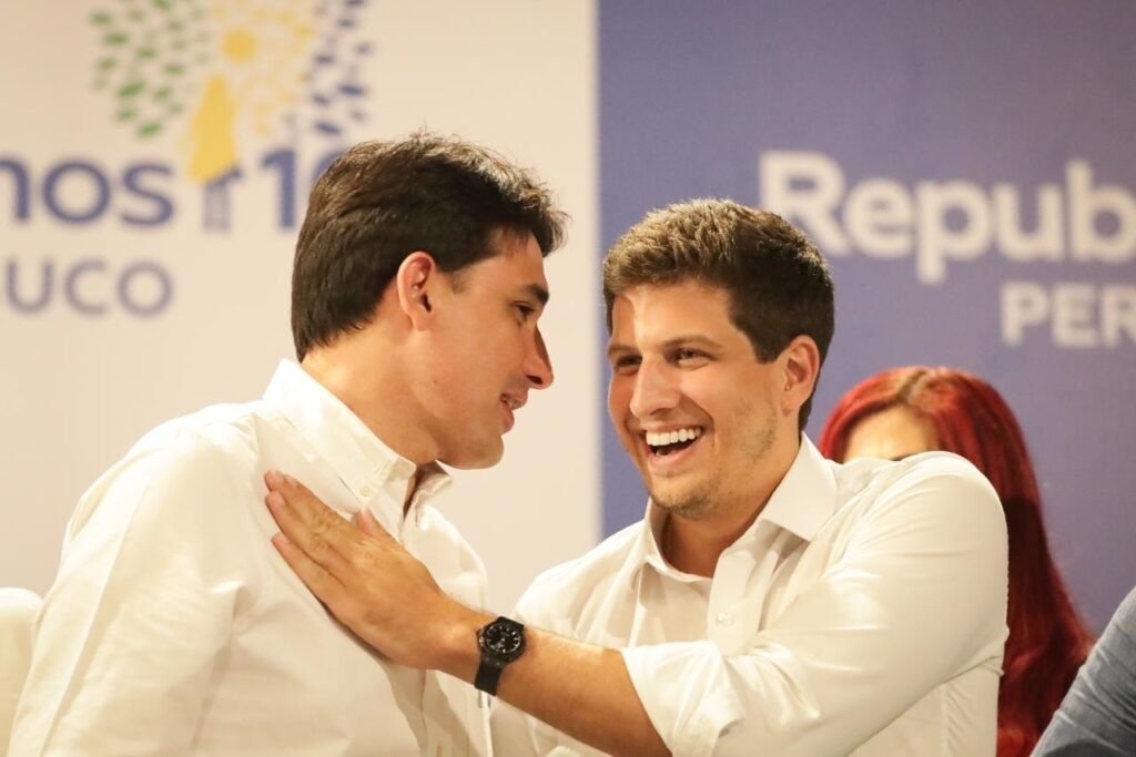 O prefeito do Recife, João Campos, cumprimenta cordialmente o ministro Silvio Costa Filho durante encontro político do partido Republicanos. Ambos aparecem sorridentes, simbolizando a aliança para as eleições de 2026 em Pernambuco.