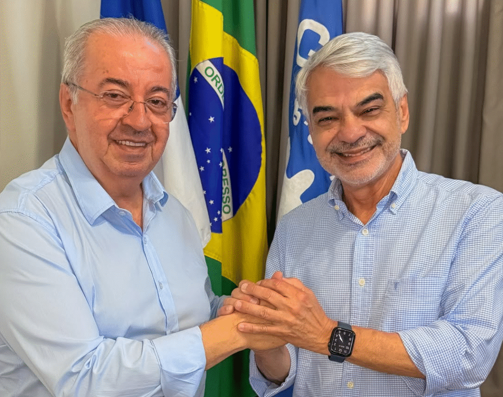 Humberto Costa e Joselito Gomes posam juntos durante reunião institucional em Gravatá com bandeiras ao fundo