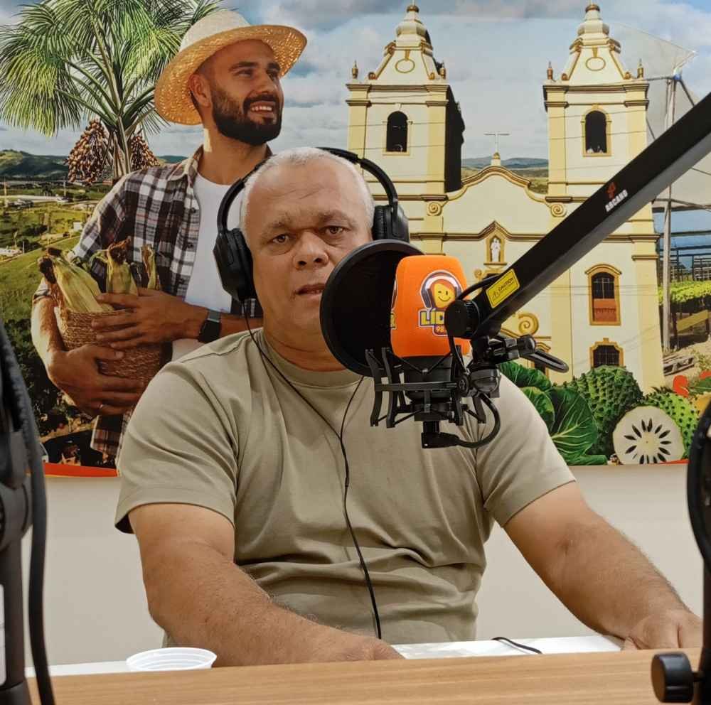Ex-prefeito de Primavera, Rômulo César, de camiseta verde e fones de ouvido, concede entrevista nos estúdios da Rádio Líder FM durante o programa Panorama Político com Ismael Alves.