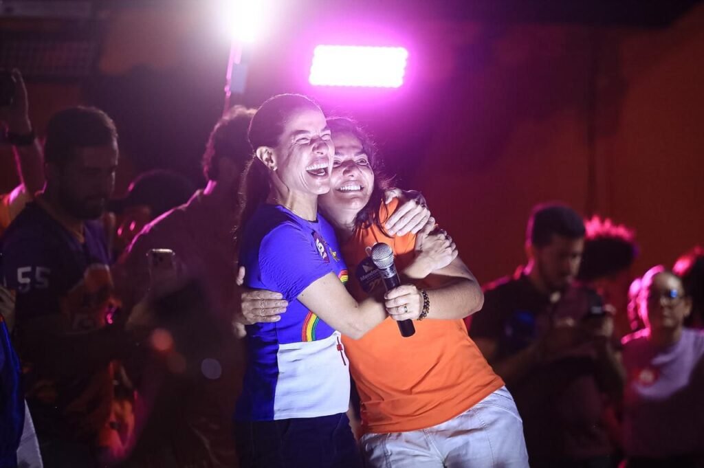 Raquel Lyra e Viviane Facundes sorrindo e se abraçando em cima do palanque durante inauguração do comitê de campanha em Gravatá.