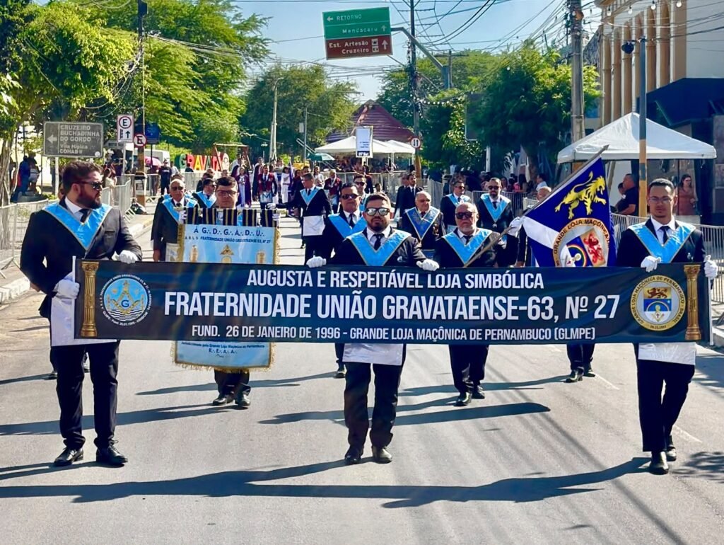 Membros da Loja Maçônica Fraternidade União Gravataense desfalam nas ruas de Gravatá no 7 de Setembro segurando uma faixa oficial.
