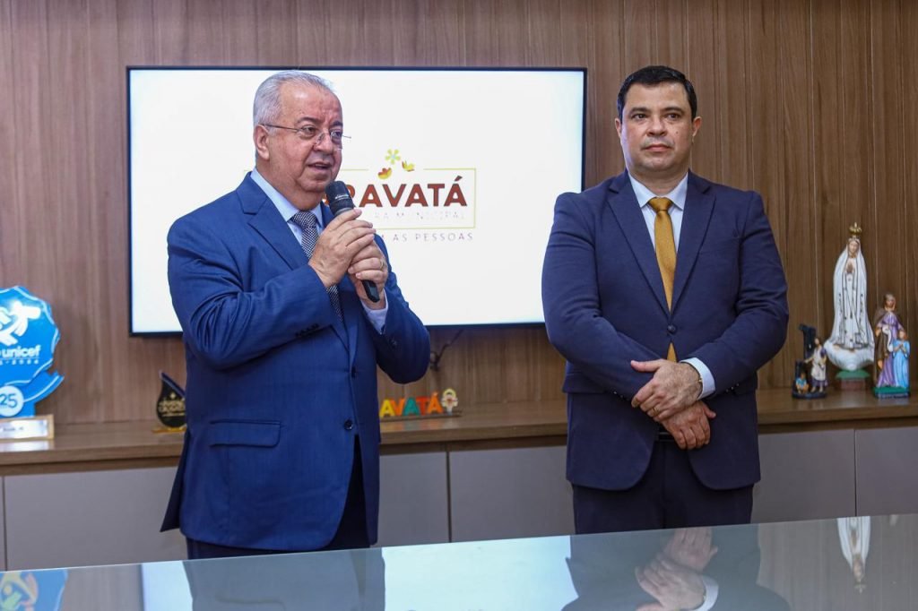 Prefeito Joselito Gomes com microfone na mão ao lado de secretário em evento oficial da Prefeitura de Gravatá.