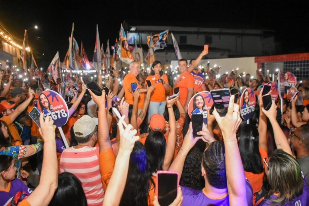 Viviane Facundes discursa com microfone ao lado do prefeito Joselito Gomes e do vice João Paulo durante evento político em Gravatá.