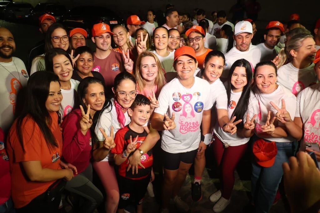 Viviane Facundes sorri cercada por apoiadores e uma criança fazendo o sinal de vitória durante o treino da corrida em Gravatá.