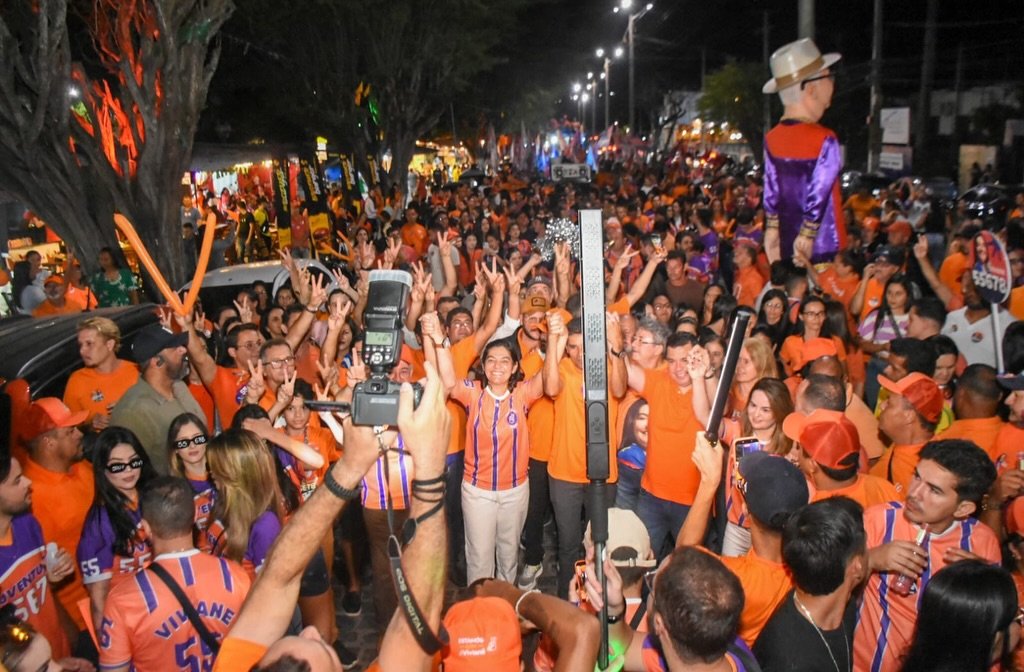 Viviane Facundes sorri e comemora com braços erguidos ao lado do prefeito Joselito Gomes em meio a multidão de apoiadores em Gravatá.
