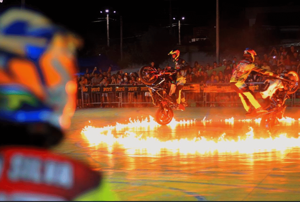 Motociclistas realizam manobra radical de grau e empinada dentro de um círculo de fogo durante apresentação noturna no Motofest em Gravatá.