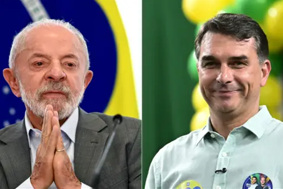 Imagem dividida ao meio mostrando o presidente Luiz Inácio Lula da Silva à esquerda, com paletó escuro e mãos postas à frente contra o fundo da bandeira do Brasil, e o senador Flávio Bolsonaro à direita, sorrindo de camisa clara em evento político com balões amarelos e verdes ao fundo.